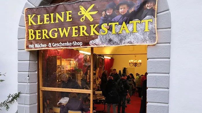 Bezaubernder Ladeneingang „Kleine Bergwerkstatt“ mit Büchern und Geschenkartikeln, voller Besucher im Inneren.