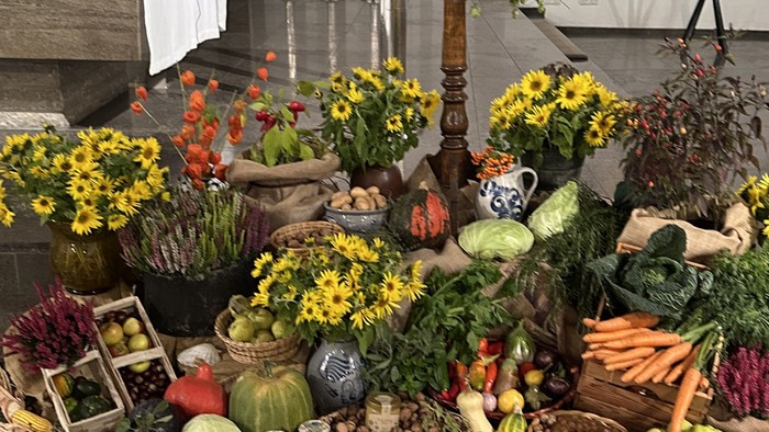 Bunte Altar-Anordnung mit frischen Lebensmitteln, Blumen, Kerzen und einem religiösen Porträt, umgeben von Opfergaben.