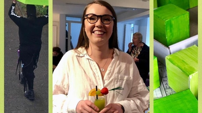 Ein Frau hält einen Apfel in einem Raum mit grünen Stühlen, um sie herum sind Menschen und ein Buffet mit Essen