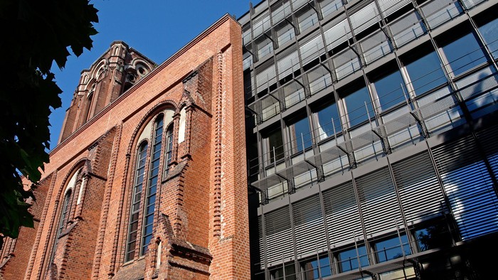 Altes Backsteingebäude neben modernem Glasbau