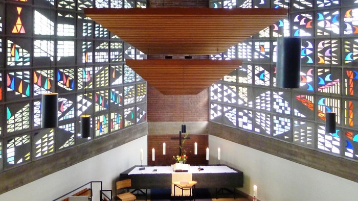 Modernes Kircheninnere mit farbenfrohen Buntglasfenstern und Holzdecke
