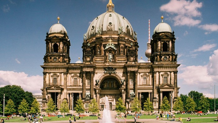 Großartige Kathedrale mit zwei Kuppeltürmen und zentralem Hauptdom, umgeben von Grünflächen und Menschen