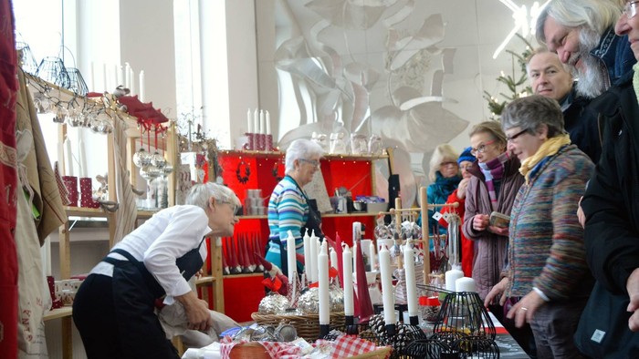 En gruppe ældre folk ser på og kigger i en butik med mange lysstaker og pynt.