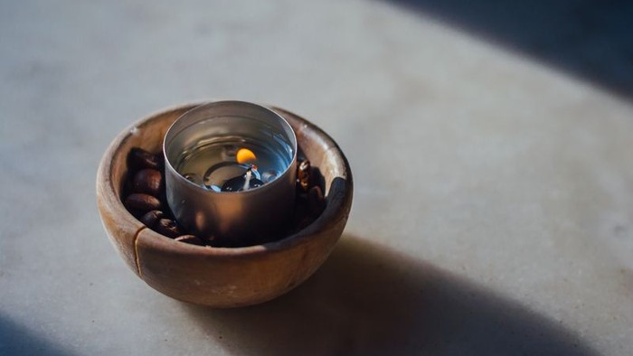 Kleine Tasse mit Kaffeebohnen in Holzschale