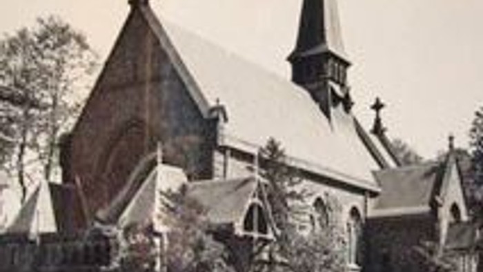 Das Bild zeigt eine alte Kirche mit hohem Turm und spitzen Dachformen.