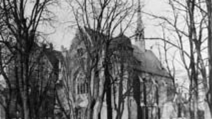 Alte Kirche mit hohen Bäumen im Winter.