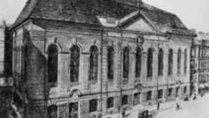 Das Bild zeigt eine historische Kirche mit hohem Turm und vielen Fenstern.