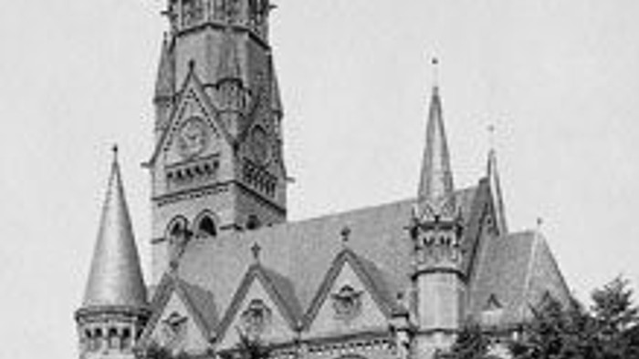 Das Bild zeigt eine große gotische Kirche mit hohem Turm und spitzen Bögen.