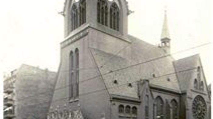 Altes Foto einer Kirche mit hohem Turm und spitzen Fenstern.