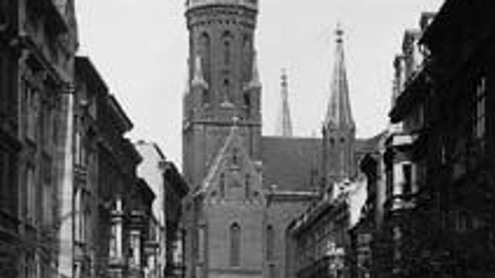 Historische Stadtansicht mit hoher Kirche und Menschen auf Straße