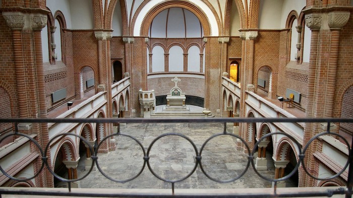 Das Bild zeigt eine große, verzierte Kirche mit gewölbten Bögen und einem steinernen Altar.