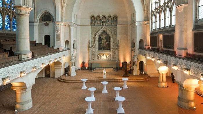 Großzügige Kirche mit hohen Bögen und weißen Stühlen