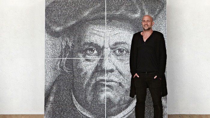 Ein Mann steht neben einem großen schwarz-weißen Portrait.