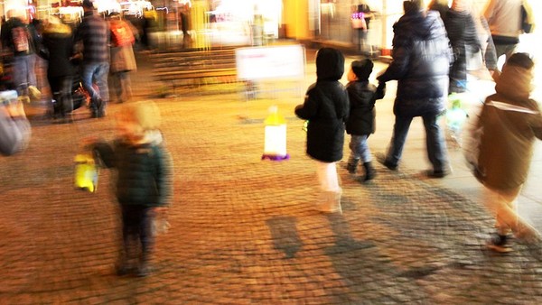unscharfes Foto vom Martinsumzug: Kinder und Eltern mit Laternen auf der Straße