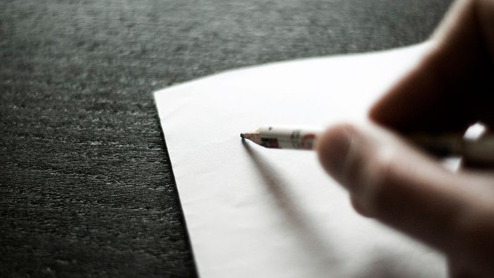 Hand schreibt mit Stift auf Papier