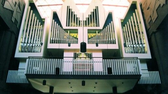 Eine große Pfeifenorgel mit mehreren Pfeifenreihen und komplexen Tastatursteuerungen in einem geräumigen Saal.