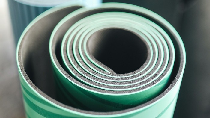 Drei zusammengerollte Yogamatten in Grün und Grau