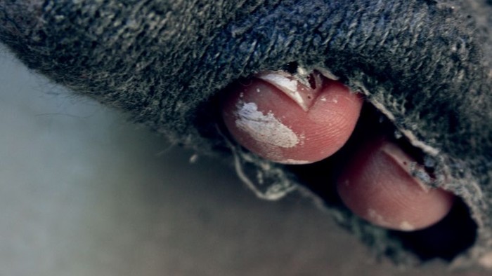Ein Finger schaut durch ein Loch in einem Stoff.
