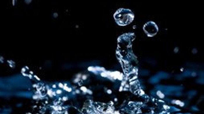 Wasser spritzt hoch auf und bildet Tropfen.