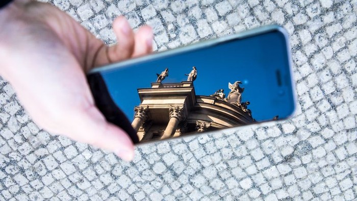 Hand hält Handy mit Bild eines Gebäudes
