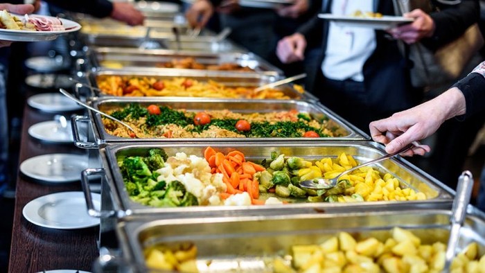 En buffetbord med forskellige retter og grønne salater