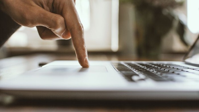 Hand tippt auf Laptop-Tastatur