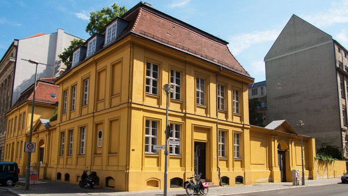 Gelbe Gebäude mit braunem Dach an belebter Straße