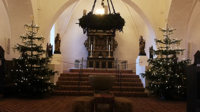 Indre del af kirke med juletømmer og lys.