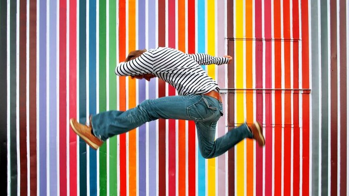 Ein Skateboarder führt einen Trick vor einer farbenfrohen Wand aus.