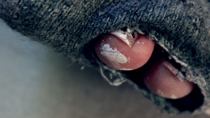 Ein Finger schaut durch ein Loch in einem Stoff.