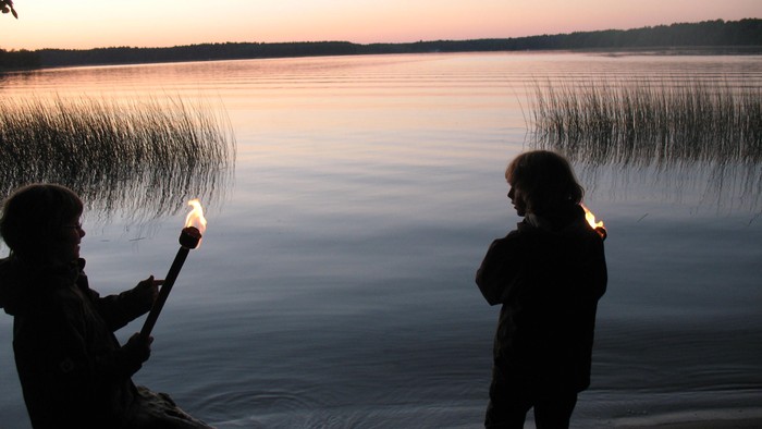 Zwei Personen am Ufer eines Sees bei Sonnenuntergang