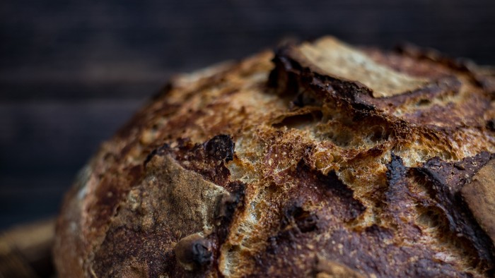 Ein frisches Brot liegt auf einem Holztisch.