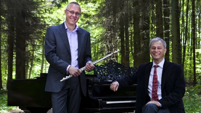 To men i formelt tøj ved et piano i skoven