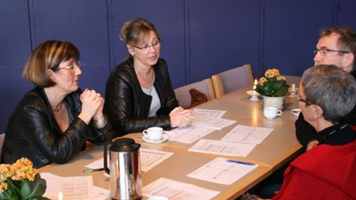 En gruppe af mennesker sidder ved et bord og diskuterer papirer.