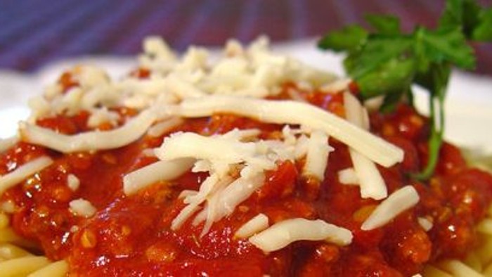 En ret med spaghetti og tomat sauce, bestøvet med ost og frisk petersilie