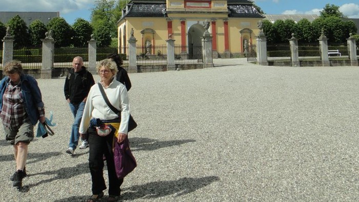 En gruppe turister går mod et historisk bygning i solskinn