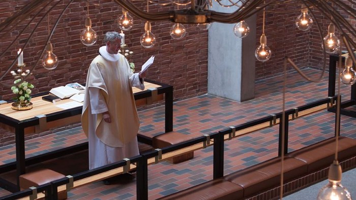 En præst står i en kirke og holder en tale.