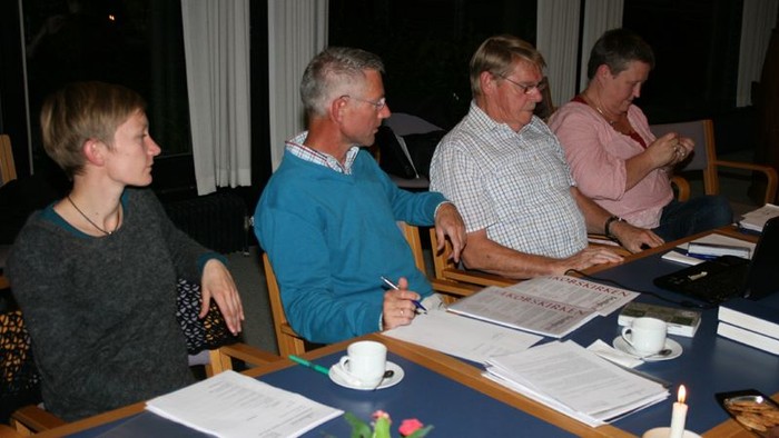 En gruppe af mennesker sidder ved et bord og diskuterer papirer.