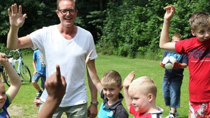 En mand og en gruppe børn spiller i en park.