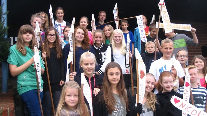 En gruppe af børn og unge står sammen med stokke og banner.
