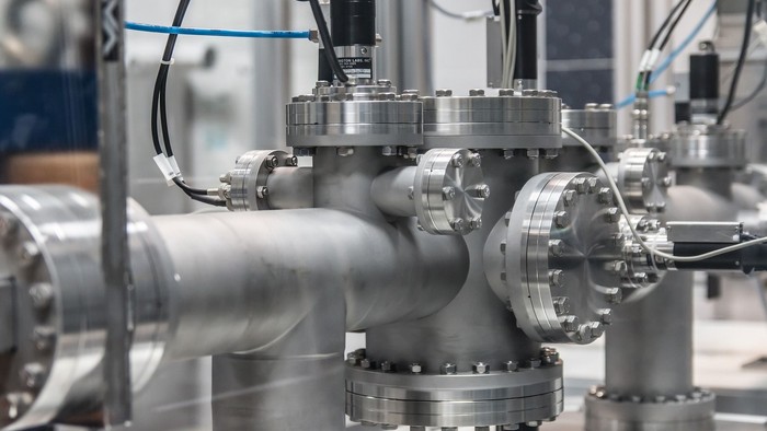 Industrielle rørinstallation med metalliske komponenter og kabler.