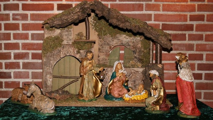 En julekreds med Jesusbarn, Maria, Josef og tre vise mænd foran en lille hytte.
