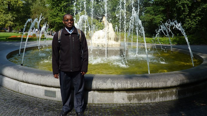 Mann steht vor einem Springbrunnen in einem Park