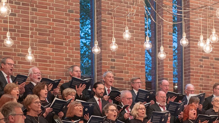 En kor sang i kirke med lysstake.
