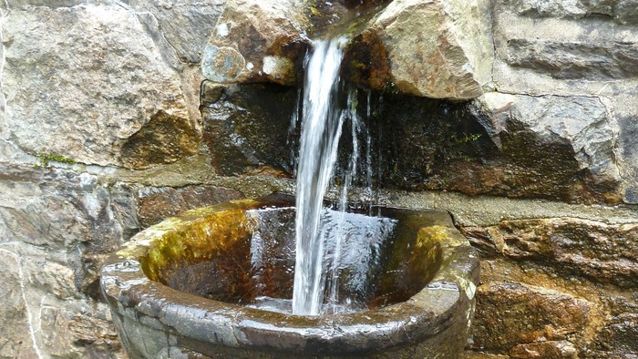 Steinbrunnen mit Wasser in einer Mauernische