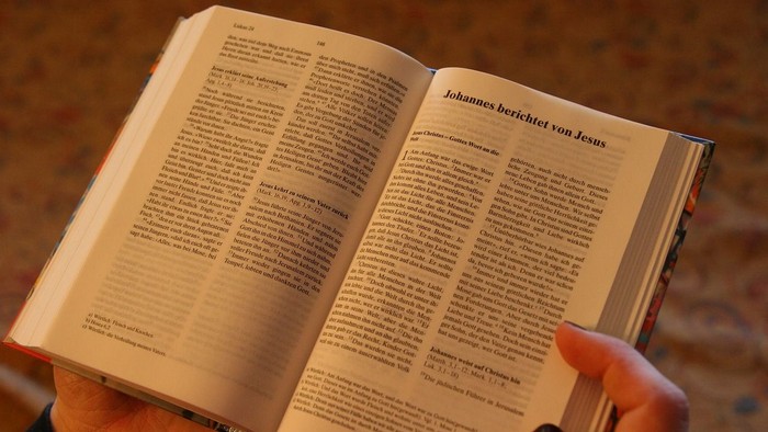 Person hält aufgeschlagenes Buch in Händen