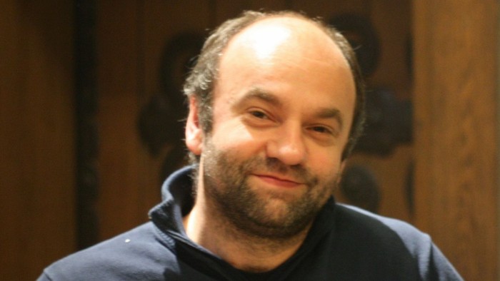 Mann hält eine Zigarre in der Hand und lächelt.