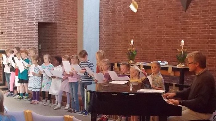 Barn og voksne synger sammen i kirke.