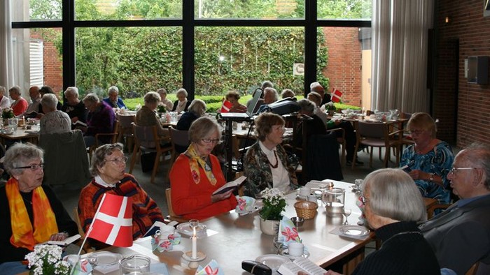 En gruppe mennesker sidder ved bord i en restaurant og spiser.