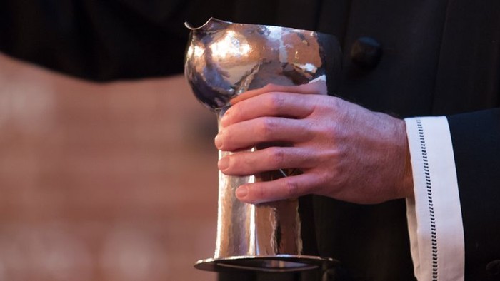 En person holder en stor, blank metalpokal.